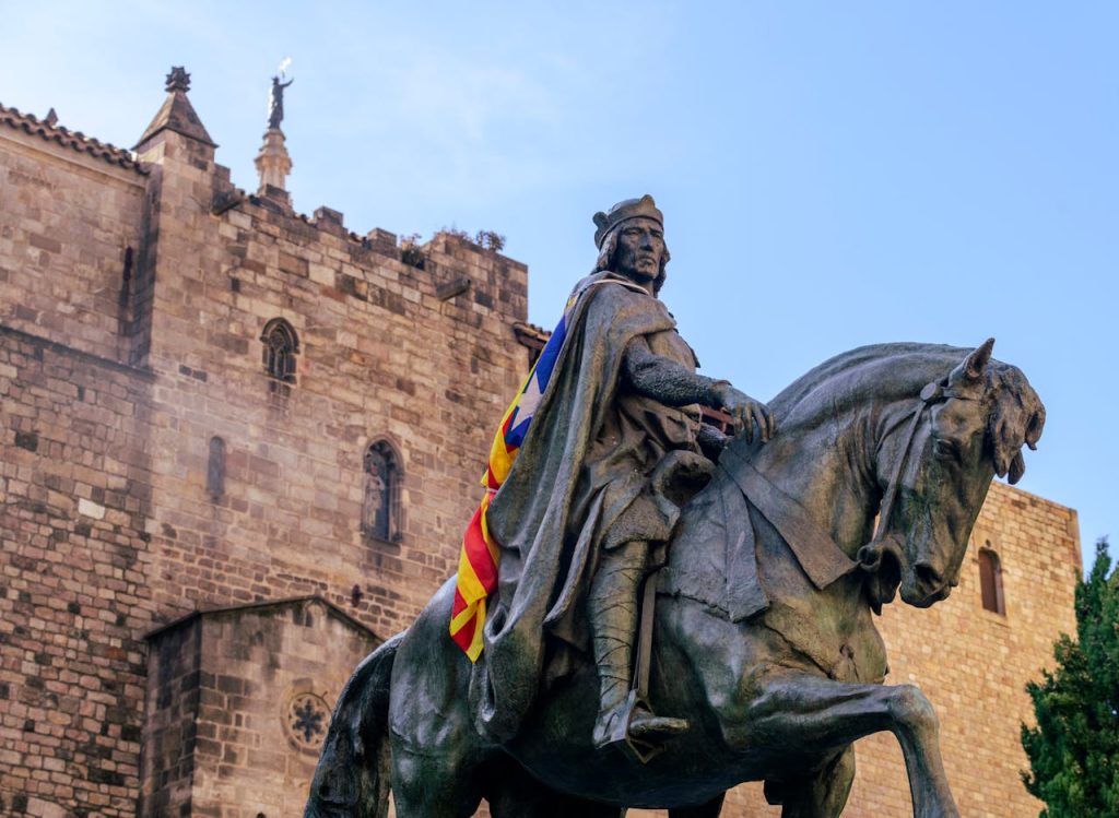 Equestrian statue with Catalan flag near a historical cathedral in Barcelona, Spain.