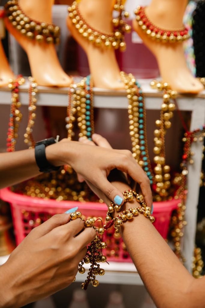 Hands trying on vibrant beaded jewelry at an indoor market stall.